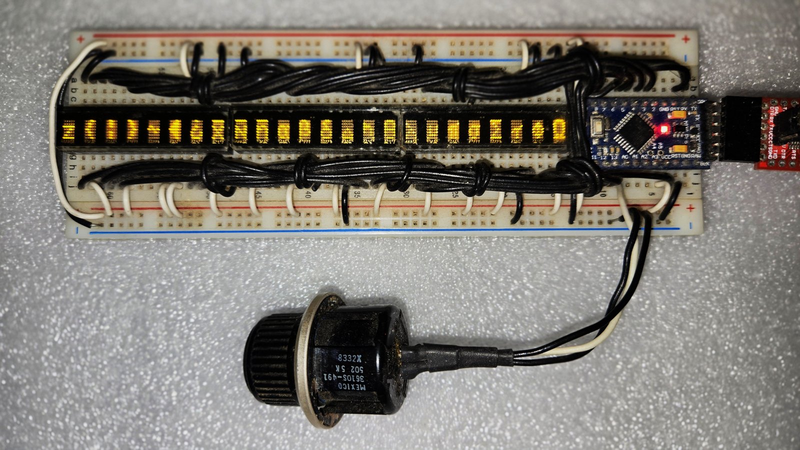 Breadboard prototype: three PDSP1880 LED character displays, MCU on the right, multi-turn pot for scroll speed